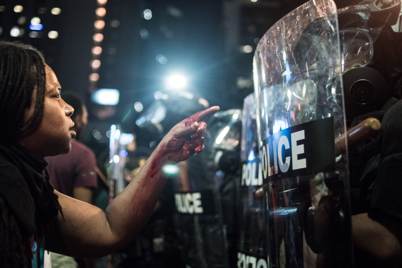 With blood covering her hand and arm, a woman points at a police officer Sept. 21, 2016, in Charlotte, N.C.Sean Rayford/Getty Images
